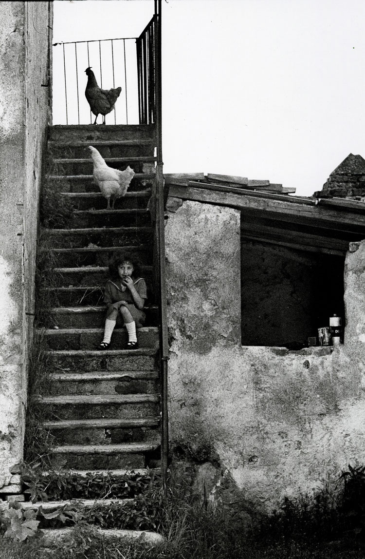 © Carla Cerati, Binasco (Milano), maggio 1975. Nel cortile della cascina una bambina gioca sulle scale di casa. (pubblicato in Luciana Martini, Cara Assuntina, Torino, Einaudi, 1976, copertina, p. nn. 73)
