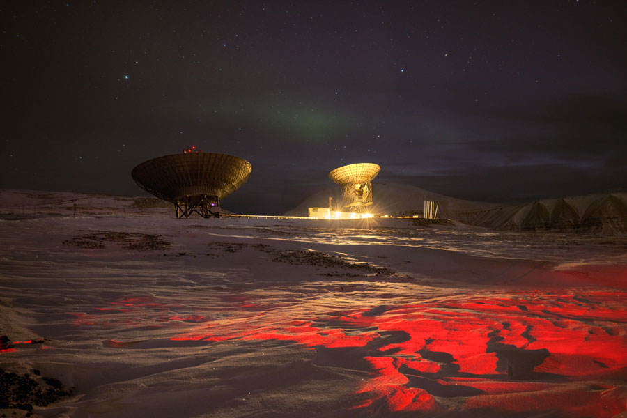 Il radar EISCAT alle Svalbard, Norvegia. Il radar, composto da due antenne (32 m e 42 m), viene utilizzato per studiare le regioni della cuspide polare e della calotta polare. È inoltre uno strumento di ricerca perfetto per le aurore boreali (visibili in modo tenue nell'immagine) grazie alla sua vicinanza al Polo Nord. © Paolo Verzone