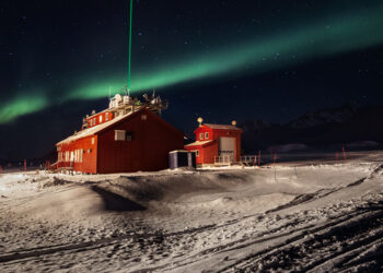 Stazione di ricerca di Ny-Ålesund, Svalbard. Il raggio laser verde (KARL, il Koldewey Aerosol Raman Lidar) emesso dall'osservatorio AWIPEV di notte, durante un'aurora boreale. Con questo strumento gli scienziati studiano l'atmosfera. © Paolo Verzone