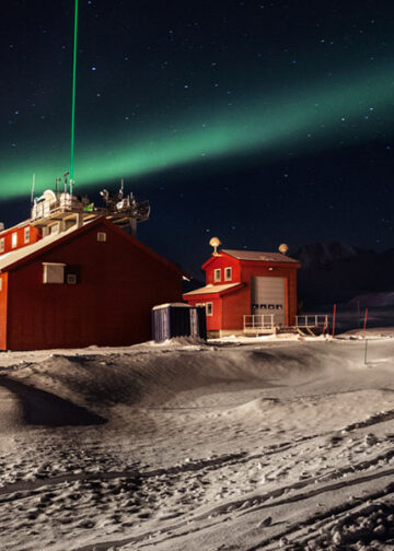 Stazione di ricerca di Ny-Ålesund, Svalbard. Il raggio laser verde (KARL, il Koldewey Aerosol Raman Lidar) emesso dall'osservatorio AWIPEV di notte, durante un'aurora boreale. Con questo strumento gli scienziati studiano l'atmosfera. © Paolo Verzone