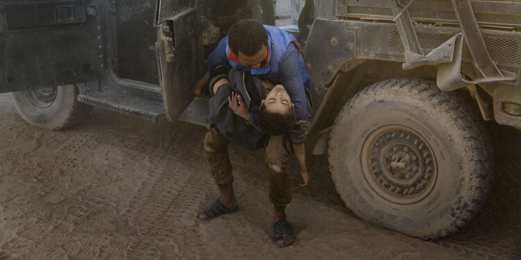 Ivor Prickett, End of the Caliphate, Un uomo collassa fuori da un veicolo blindato presso la postazione di pronto soccorso di Mosul est, stringendo il corpo del fratello minore ucciso qualche momento prima da un attacco di mortaio dell’ISIS, Mosul, Iraq, 2016, Courtesy and © Ivor Prickett