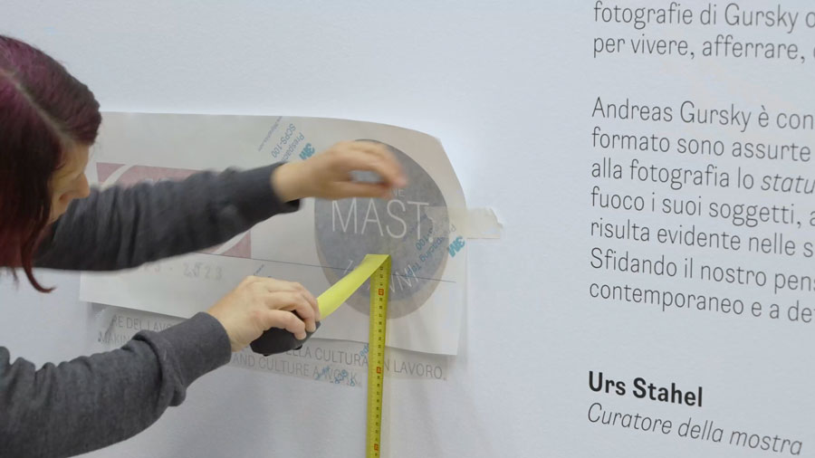 Una persone si occupa dell'allestimento dei testi lungo il percorso espositivo di "Andreas Gursky, Visual Visual Spaces of Today".