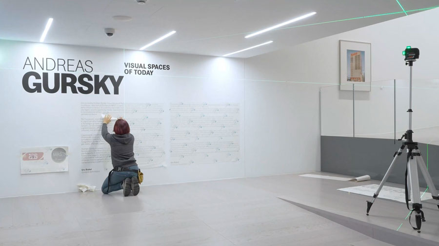 Una persone si occupa dell'allestimento dei testi lungo il percorso espositivo di "Andreas Gursky, Visual Visual Spaces of Today".