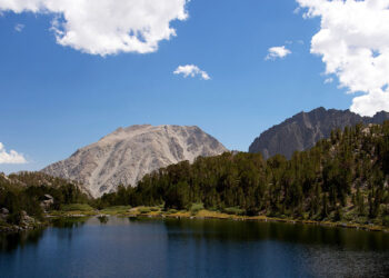 un lago alpino con un cielo costellato di nuvolette bianche
