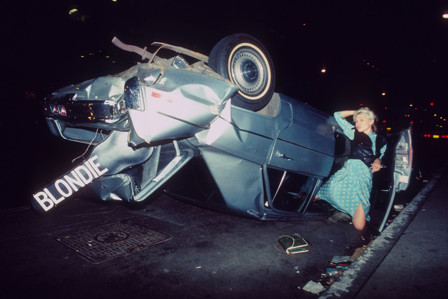 © Bob Gruen, Debbie Harry of Blondie in a wrecked car on 6th Avenue and 50th Street, NYC, 1976, courtesy of the artist and The Music Photo Gallery