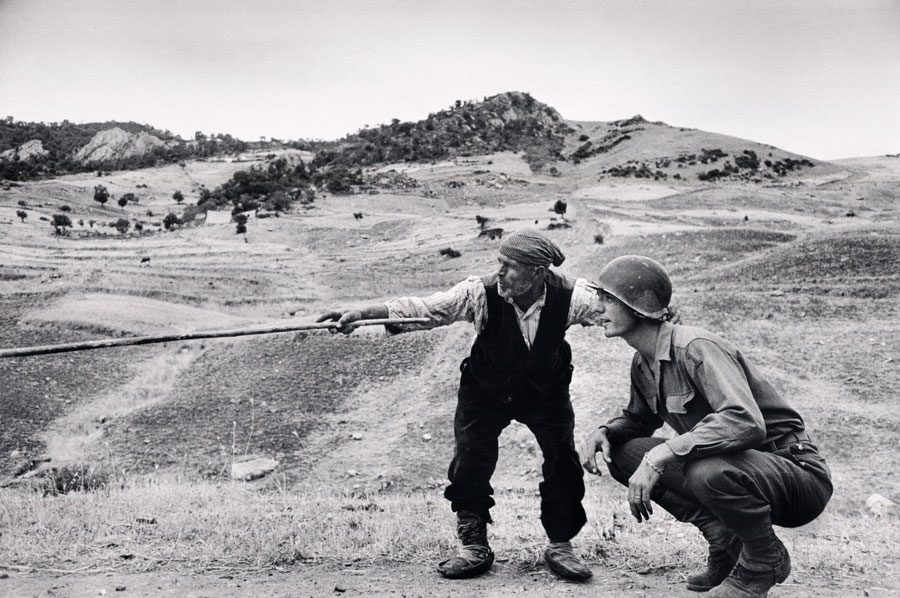Un siciliano spiega ad un ufficiale americano quale strana hanno percorso i tedeschi vicino a Troina, Sicilia, 4 - 5 agosto 1943. © Robert Capa © International Center of Photography / Magnum Photos