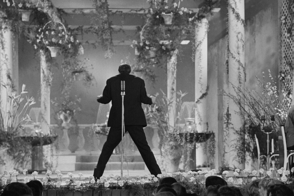 Adriano Celentano fa scandalo voltando le spalle al pubblico durante la sua esibizione all'XI Festival di Sanremo in cui canta 24000 baci, 1961. Fotografia di Franco Gremignani