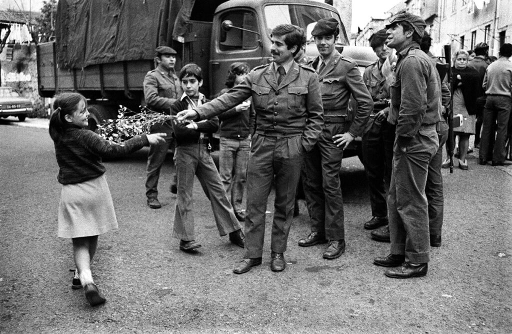 Giovani soldati ricevono l'omaggio floreale da una bambina. Lisbona, aprile 1974 © Paola Agosti