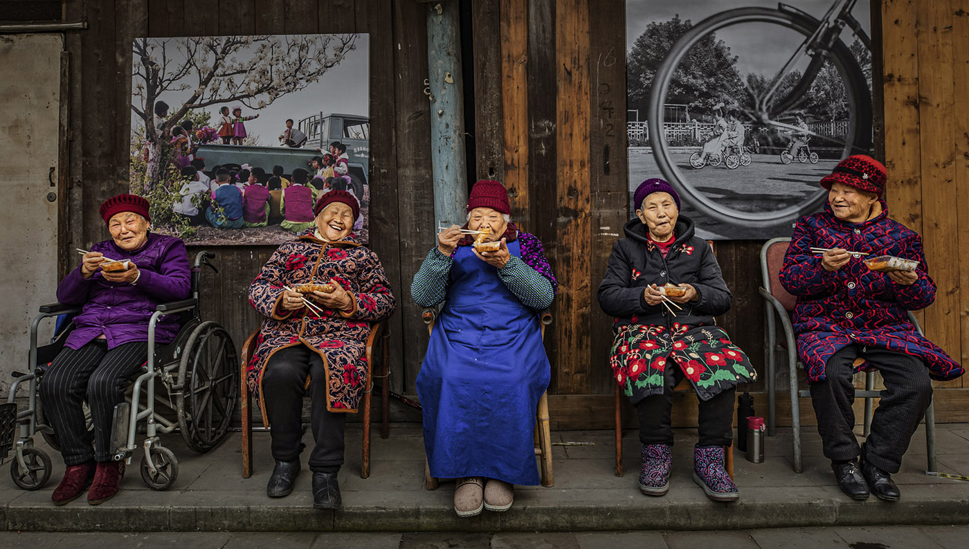 La fotografa cinese Xiaoling Li è stata incoronata Vincitrice Assoluta dei World Food Photography Awards, sponsorizzati da Bimi, e ha ricevuto un premio di 5.000 sterline per una commovente immagine che ritrae anziani vicini di casa riuniti a condividere storie mentre gustano involtini primavera del Sichuan.