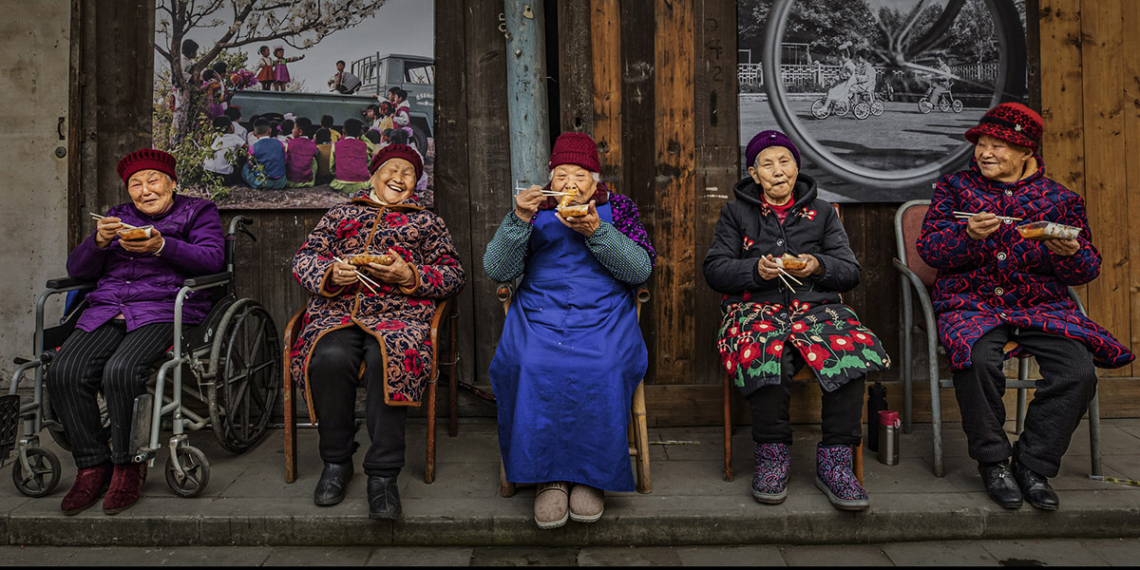 La fotografa cinese Xiaoling Li è stata incoronata Vincitrice Assoluta dei World Food Photography Awards, sponsorizzati da Bimi, e ha ricevuto un premio di 5.000 sterline per una commovente immagine che ritrae anziani vicini di casa riuniti a condividere storie mentre gustano involtini primavera del Sichuan.