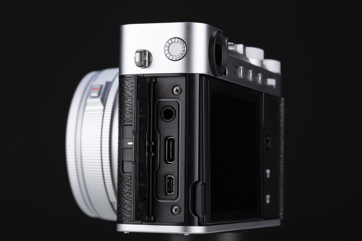 La particolarità di tutte le Fujifilm con sensore da 40 megapixel, e quindi anche della X-E5, è quella di sfruttare l’alta densità di pixel per simulare un moltiplicatore di focale digitale su due livelli. Il primo livello applica un ingrandimento di 1,4x, riducendo la risoluzione da 7728x5152 a circa 5472x3648 pixel. Il secondo livello prevede un ingrandimento 2x, che abbassa la risoluzione a circa 3864x2592 pixel. Le connessioni della X-E5 sono essenziali, con la presa per il microfono affiancata a quella USB-C/cuffie e alla HDMI di taglia piccola. Il tasto per attivare il Bluetooth è, curiosamente, ospitato nel fondello.
