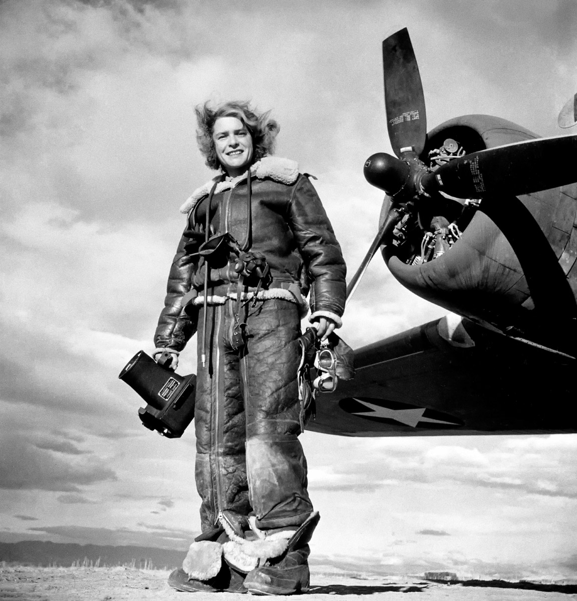 Margaret Bourke-White, vestita con una tuta di volo, impugna una macchina fotografica aerea e posa davanti al bombardiere Flying Fortress, dal quale ha realizzato fotografie di guerra durante l’attacco statunitense su Tunisi. Algeria, 1943. Margaret Bourke-White/The LIFE Picture Collection/Shutterstock
