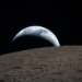 Tramonto della Terra ripreso attraverso il finestrino della navicella Orion alle 18:41 EDT del 6 aprile 2026, durante il sorvolo della Luna da parte dell’equipaggio di Artemis II. Una Terra di un blu attenuato, solcata da nubi bianche luminose, tramonta dietro la superficie lunare punteggiata di crateri. La parte in ombra della Terra è immersa nella notte. Sul lato illuminato del pianeta si distinguono nubi in movimento sopra la regione di Australia e Oceania. In primo piano, il cratere Ohm mostra bordi terrazzati e un fondo piatto interrotto da picchi centrali. I picchi centrali si formano nei crateri complessi quando la superficie lunare, liquefatta dall’impatto, risale verso l’alto durante la formazione del cratere. © Photo Credits: NASA
